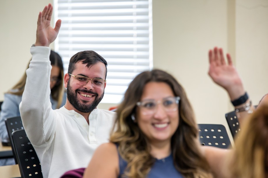 Student in Glasses Raising Hand to Contribute his Thoughts in MUA Classroom.