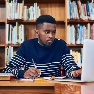 A Man Sitting at a Desk, Focused on his Laptop.