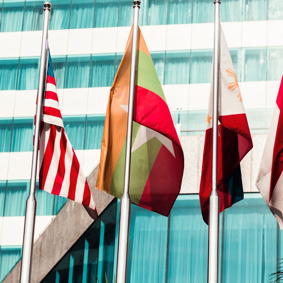 A collection of flags displayed in front of a building, representing various nations.