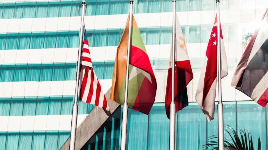 A collection of flags displayed in front of a building, representing various nations.